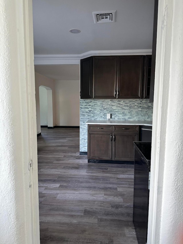 kitchen with crown molding, backsplash, dark brown cabinetry, and dark hardwood / wood-style flooring