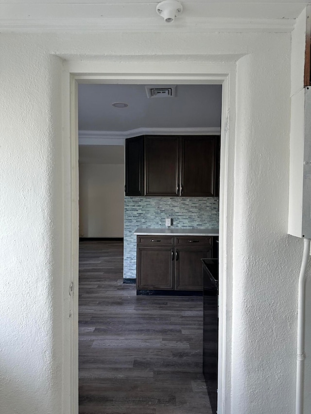 kitchen with dark brown cabinetry, ornamental molding, dark hardwood / wood-style flooring, and tasteful backsplash