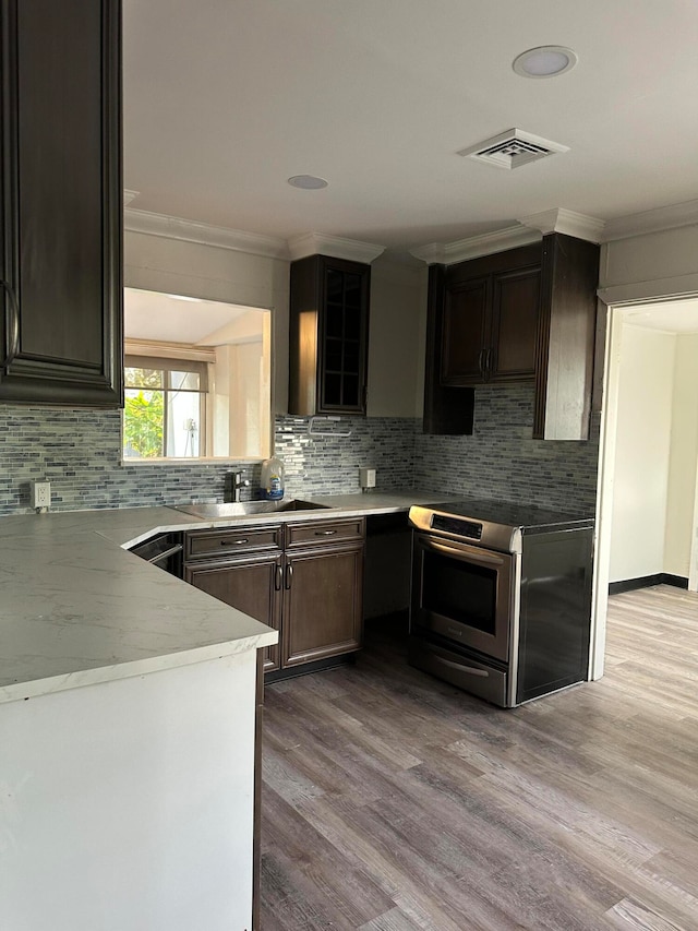 kitchen featuring light hardwood / wood-style flooring, ornamental molding, electric range, and tasteful backsplash