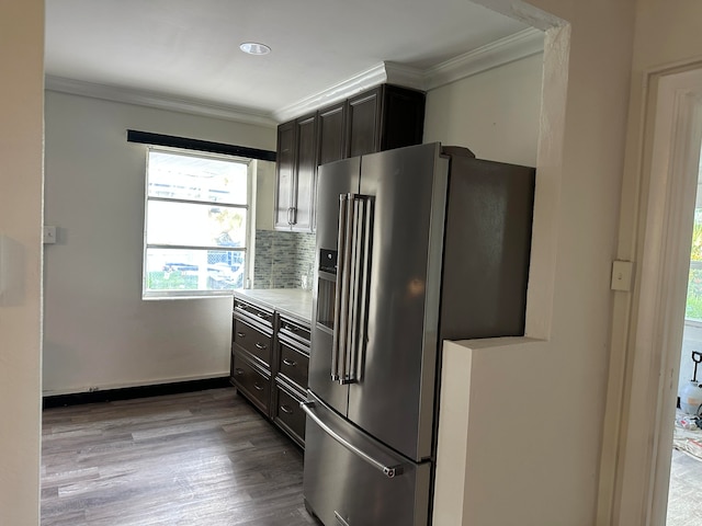 kitchen featuring high end fridge, light wood-type flooring, tasteful backsplash, and crown molding