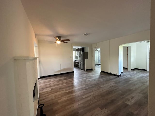 unfurnished living room with ceiling fan, dark hardwood / wood-style flooring, and a tile fireplace