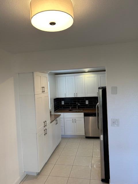 kitchen with backsplash, white cabinets, sink, appliances with stainless steel finishes, and light tile patterned flooring