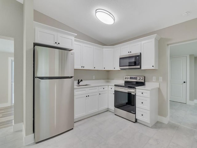 kitchen with white cabinetry, stainless steel appliances, lofted ceiling, and light wood-type flooring