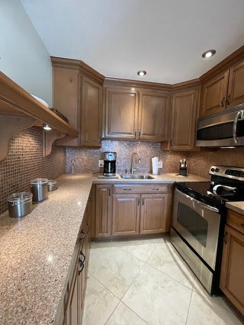 kitchen with light stone countertops, tasteful backsplash, stainless steel appliances, and sink