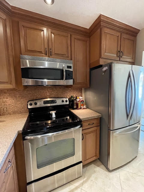 kitchen featuring stainless steel appliances, decorative backsplash, and light tile patterned floors