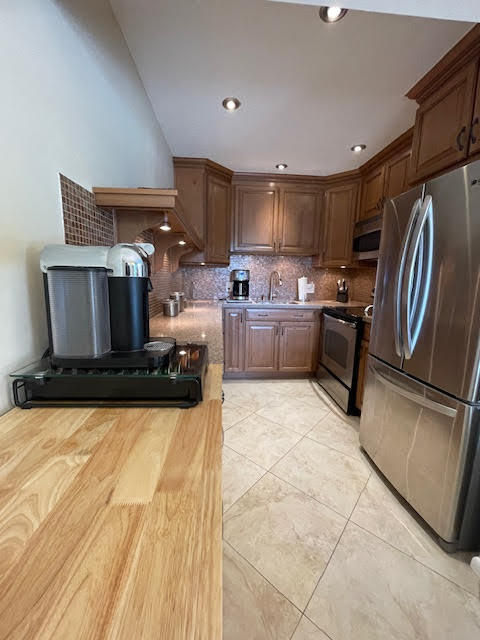 kitchen featuring wood counters, tasteful backsplash, stainless steel appliances, and sink