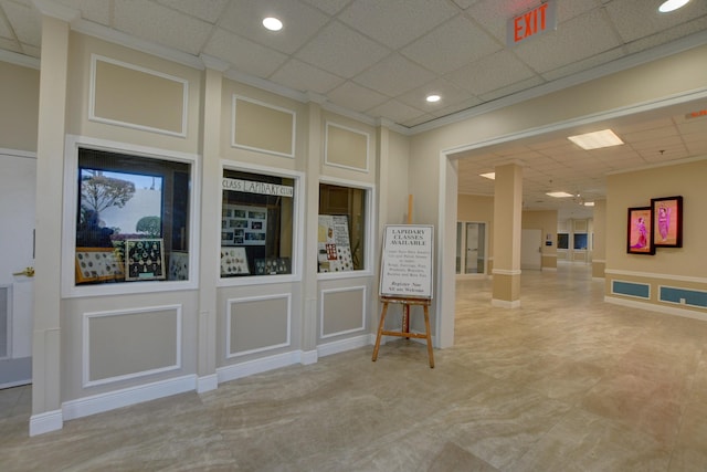 interior space featuring a paneled ceiling and ornate columns