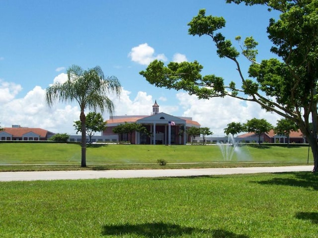 surrounding community with a water view and a lawn