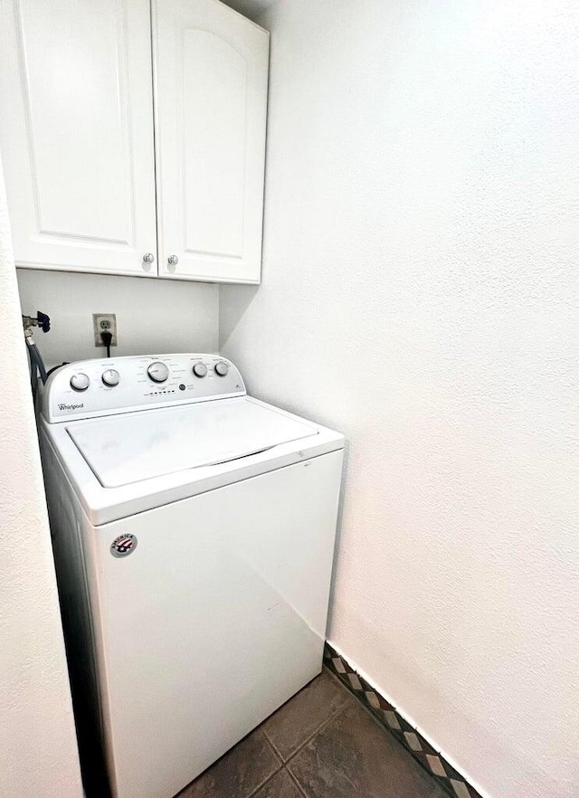 washroom with cabinets, dark tile patterned flooring, and washer / dryer