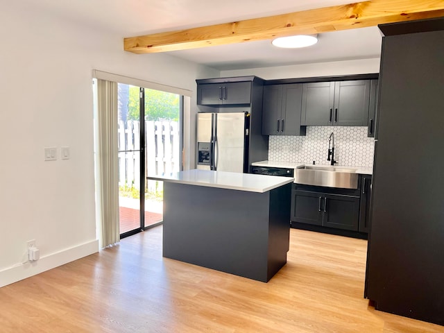 kitchen with sink, stainless steel fridge with ice dispenser, a center island, light wood-type flooring, and decorative backsplash