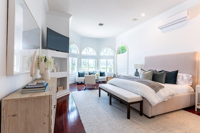 bedroom with a textured ceiling, ornamental molding, dark wood-type flooring, and a wall unit AC