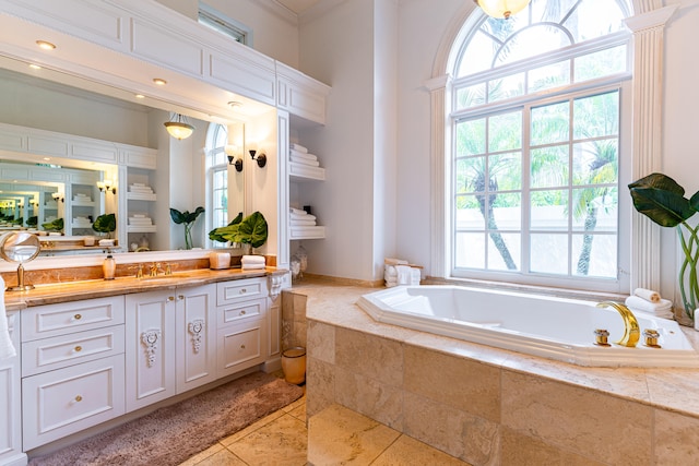 bathroom with ornamental molding, tiled bath, vanity, and tile patterned flooring