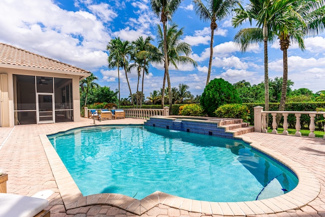 view of swimming pool featuring a sunroom, an in ground hot tub, and a patio area