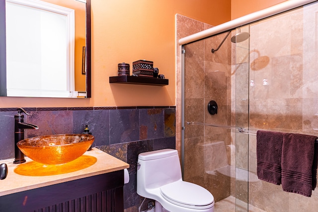 bathroom featuring tile walls, a shower with door, vanity, and toilet