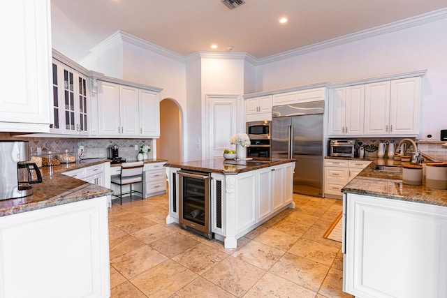 15495 Tall Oak Ave, Delray Beach, FL 33446 - kitchen with a sink, built in appliances, beverage cooler, arched walkways, and dark stone counters