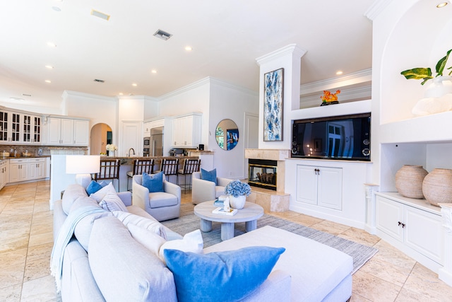 living room with crown molding, sink, and a tile fireplace