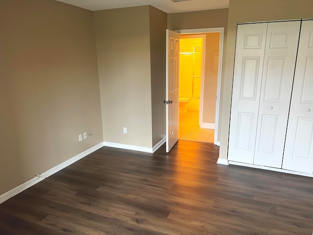 unfurnished bedroom with a closet and dark wood-type flooring