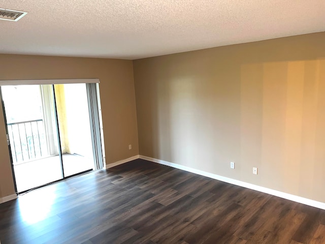 empty room featuring a textured ceiling and dark hardwood / wood-style floors