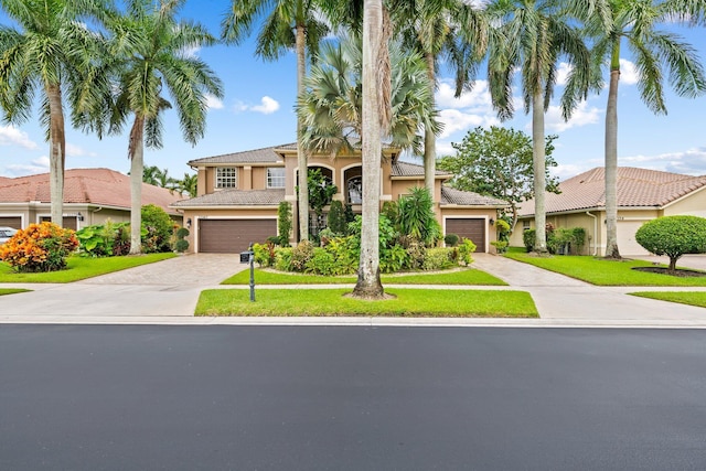 mediterranean / spanish home with a garage and a front lawn