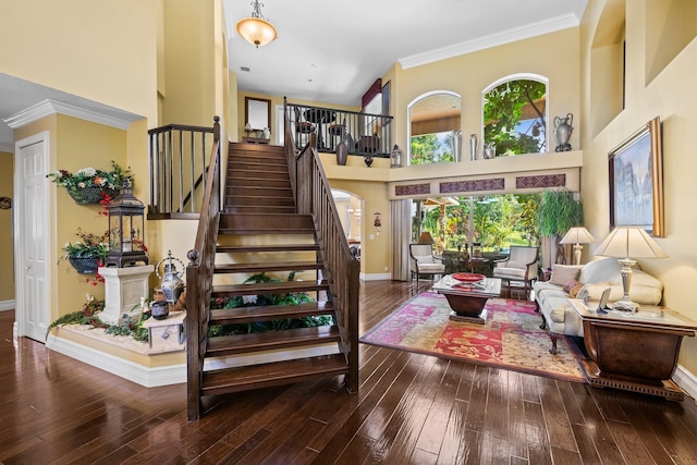 stairway with a towering ceiling, hardwood / wood-style floors, and crown molding