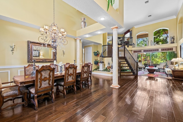 dining room with wood-type flooring, an inviting chandelier, ornamental molding, and ornate columns