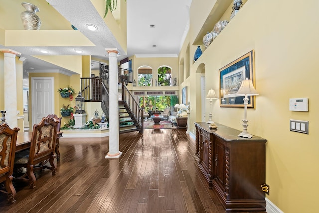 foyer entrance featuring hardwood / wood-style floors, crown molding, and ornate columns