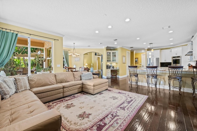 living room featuring a textured ceiling, dark hardwood / wood-style flooring, an inviting chandelier, and crown molding