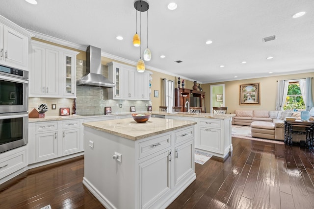 kitchen with white cabinets, wall chimney exhaust hood, and pendant lighting