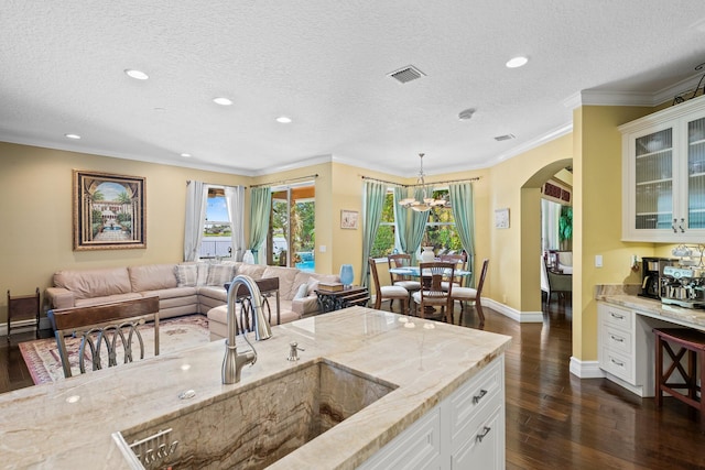 kitchen with light stone countertops, a textured ceiling, hanging light fixtures, dark hardwood / wood-style flooring, and white cabinetry