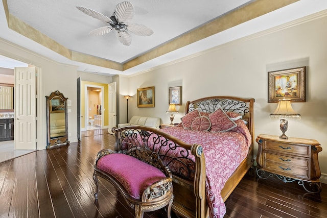 bedroom featuring ensuite bathroom, a raised ceiling, ceiling fan, and hardwood / wood-style flooring