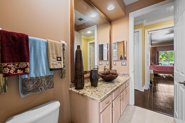 bathroom with crown molding, vanity, and toilet