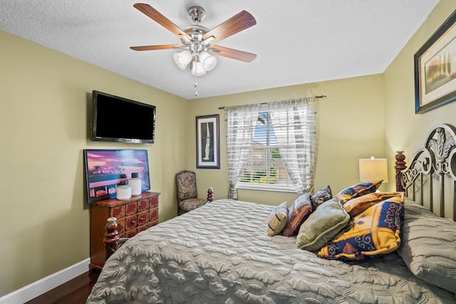 bedroom with a textured ceiling, ceiling fan, and dark hardwood / wood-style floors