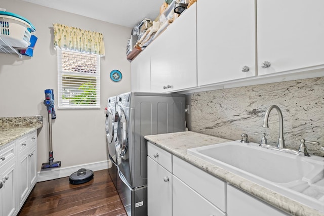 clothes washing area featuring sink, dark wood-type flooring, cabinets, and washing machine and dryer