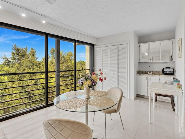 tiled dining space with a textured ceiling, plenty of natural light, and sink