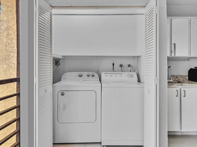 laundry area featuring light tile patterned floors, washer and clothes dryer, and sink