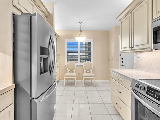 kitchen featuring hanging light fixtures, cream cabinetry, decorative backsplash, light tile patterned flooring, and appliances with stainless steel finishes