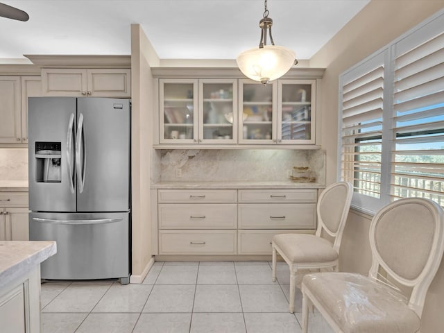 kitchen with tasteful backsplash, stainless steel fridge, decorative light fixtures, and cream cabinetry