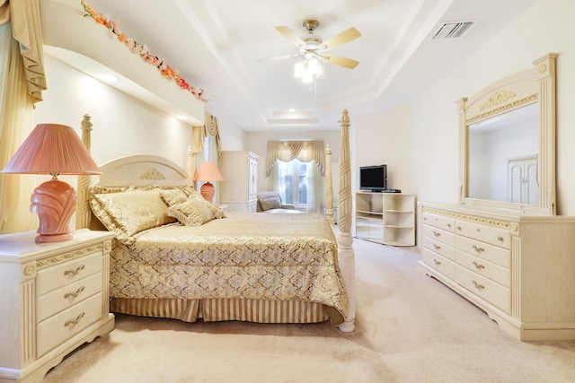 carpeted bedroom featuring a raised ceiling and ceiling fan