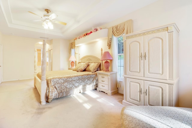 carpeted bedroom featuring a tray ceiling and ceiling fan