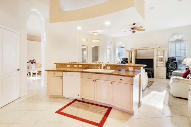 kitchen with light stone counters, sink, light tile patterned floors, white dishwasher, and ceiling fan