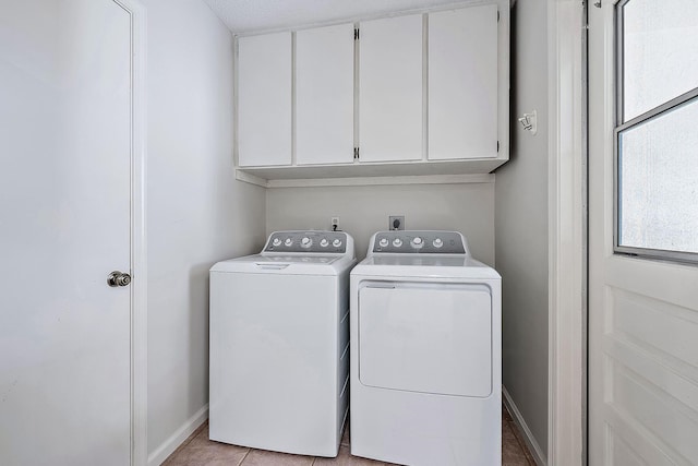 laundry room featuring a textured ceiling, washer and clothes dryer, light tile patterned floors, and cabinets