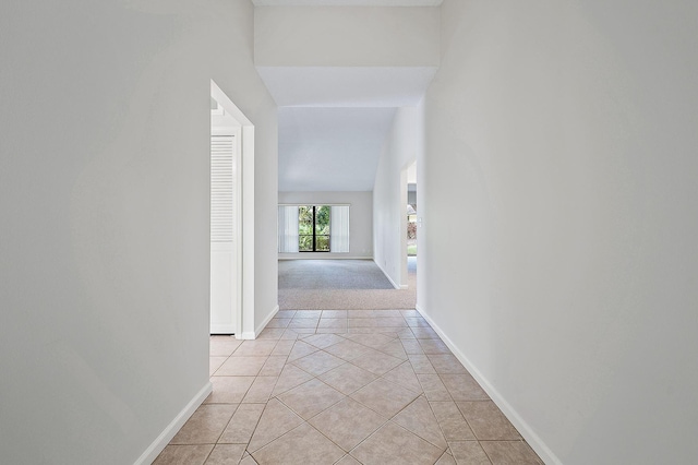 hallway featuring vaulted ceiling and light tile patterned floors