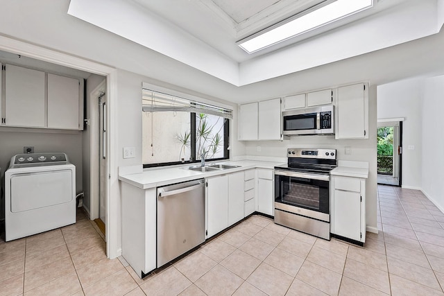 kitchen with washer / clothes dryer, sink, stainless steel appliances, and white cabinets