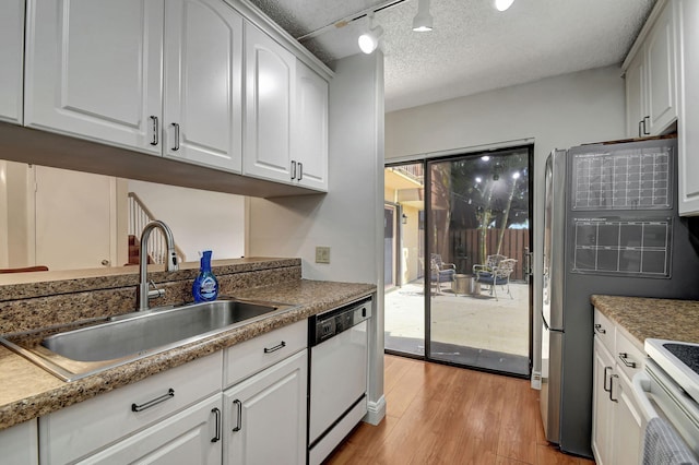 kitchen featuring white cabinetry, white dishwasher, track lighting, light hardwood / wood-style flooring, and sink