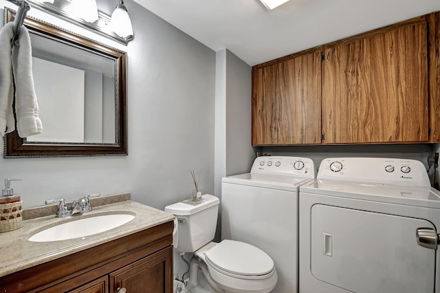 bathroom featuring washing machine and clothes dryer, vanity, and toilet