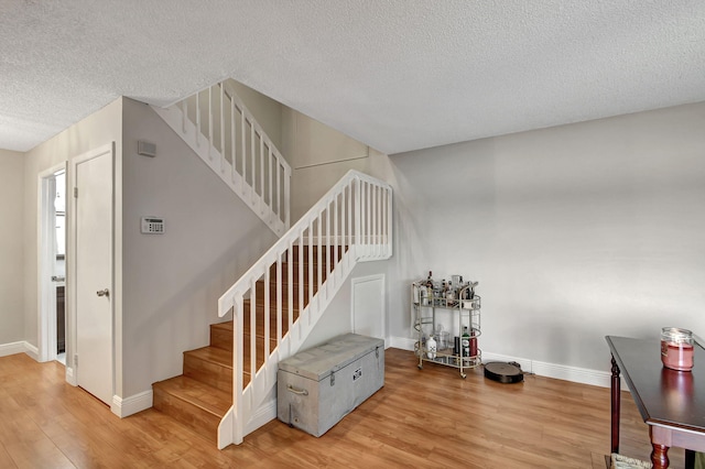 staircase with hardwood / wood-style flooring and a textured ceiling