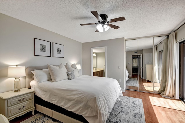 bedroom with a closet, a textured ceiling, light hardwood / wood-style flooring, connected bathroom, and ceiling fan