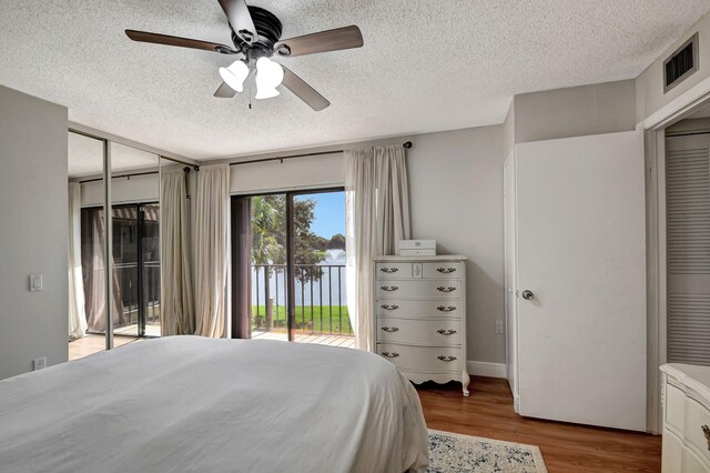 bedroom with a closet, a textured ceiling, hardwood / wood-style flooring, access to outside, and ceiling fan