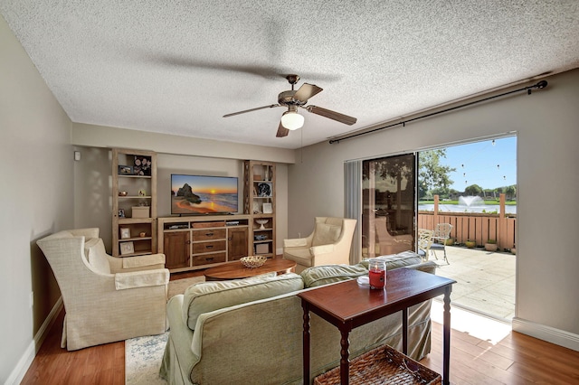 living room with a textured ceiling, hardwood / wood-style floors, and ceiling fan