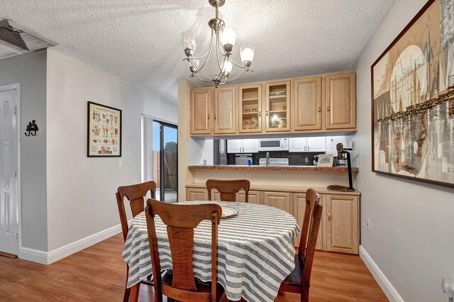 dining space featuring a chandelier, light hardwood / wood-style floors, and a textured ceiling